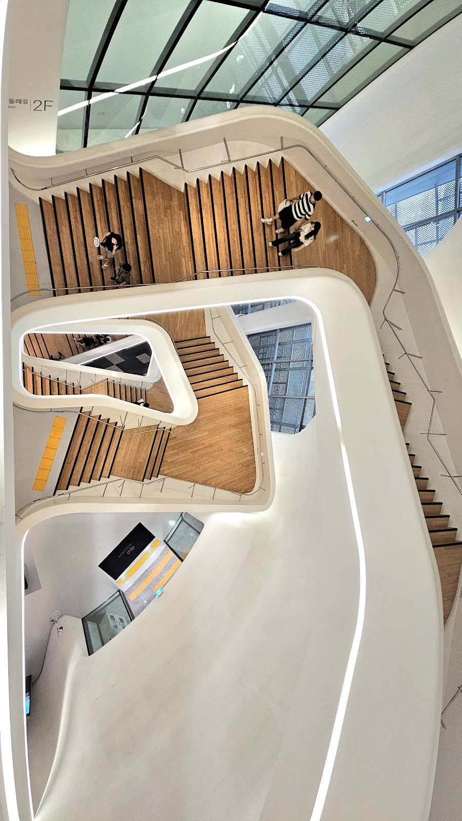 DDP Dongdaemun Design Plaza — the organic interior staircase, Zaha Hadid's biomorphic white volumes with warm wood accents